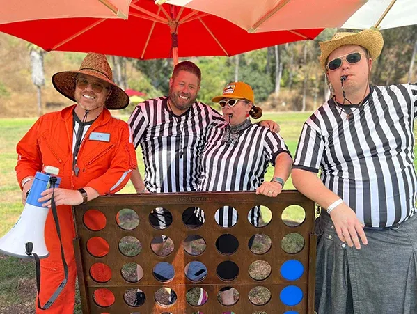 Referees posing behind a giant Connect Four board