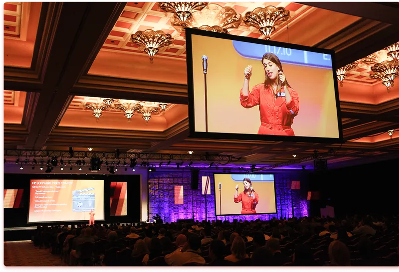 Event host addressing a large conference audience from a stage